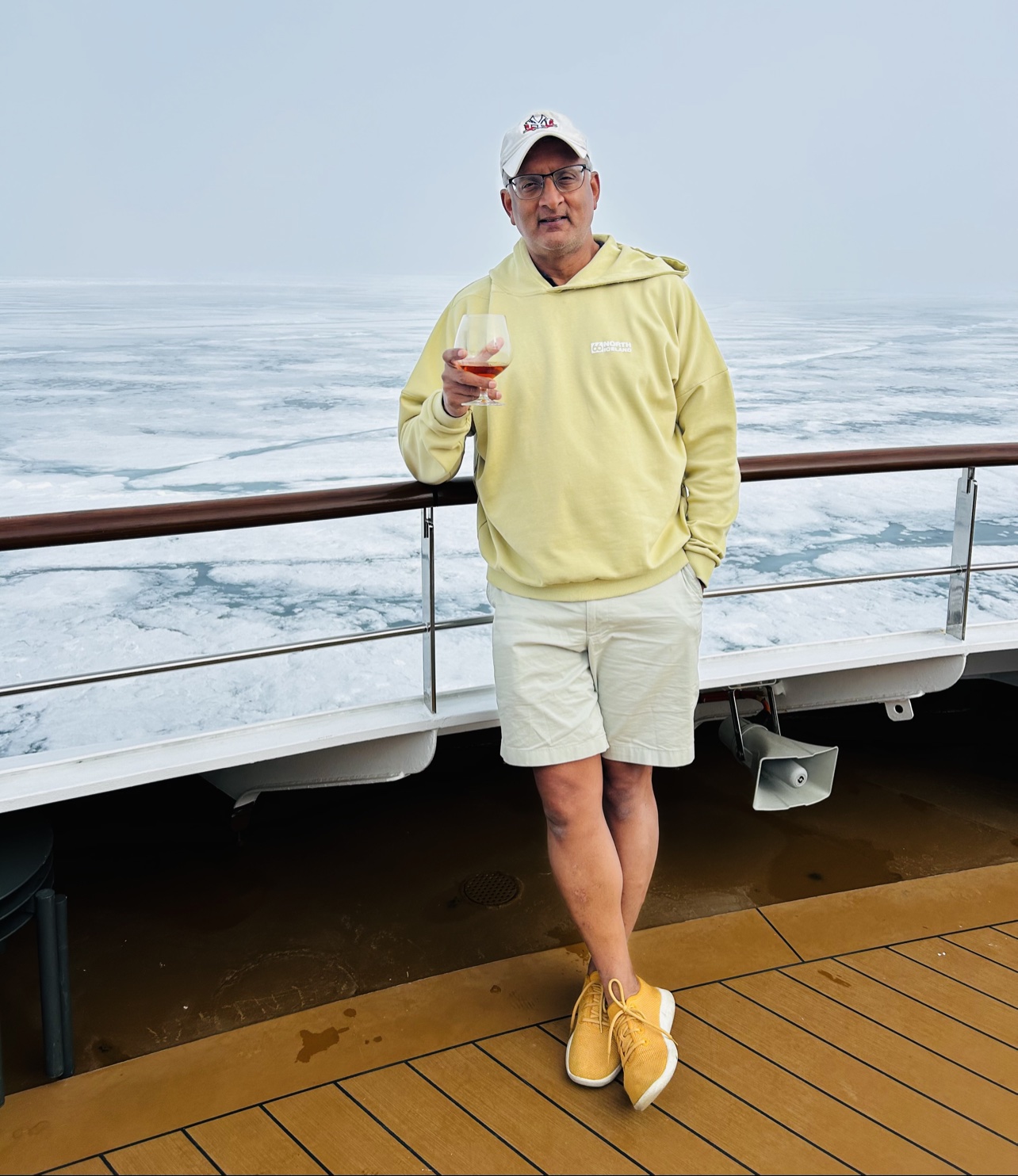 Ash in shorts on deck with a glass, pack ice behind the ship